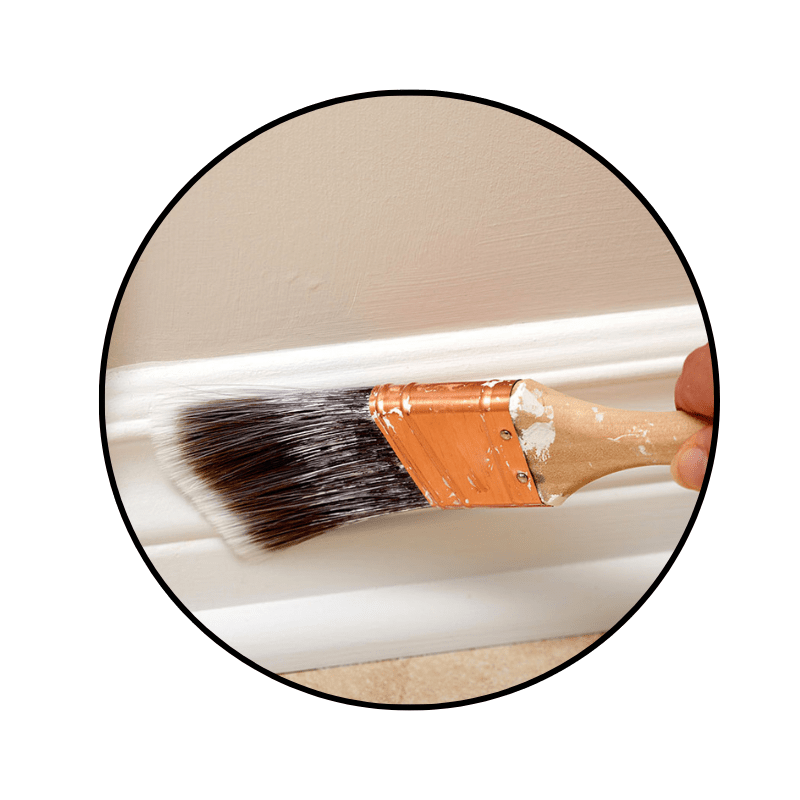 paint brush, brushing white paint onto trim and baseboards in the interior of a home