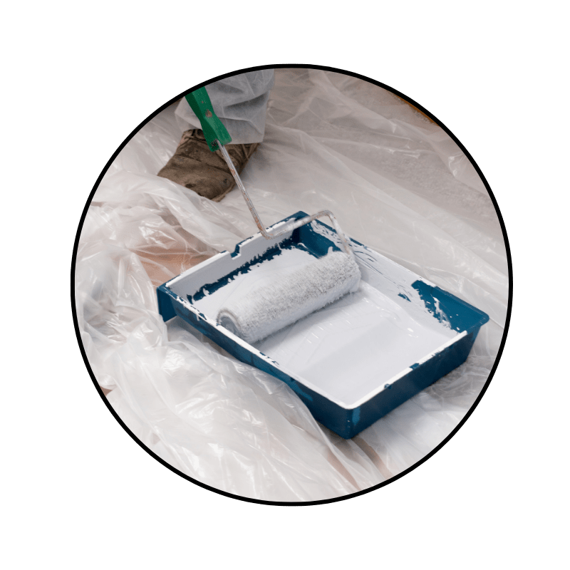 paint roller being dipped into a paint tray and liner on top of a drop cloth